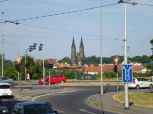 Foreground: A busy traffic intersection. Background: The Basilica of St. Peter and St. Paul in the distance.